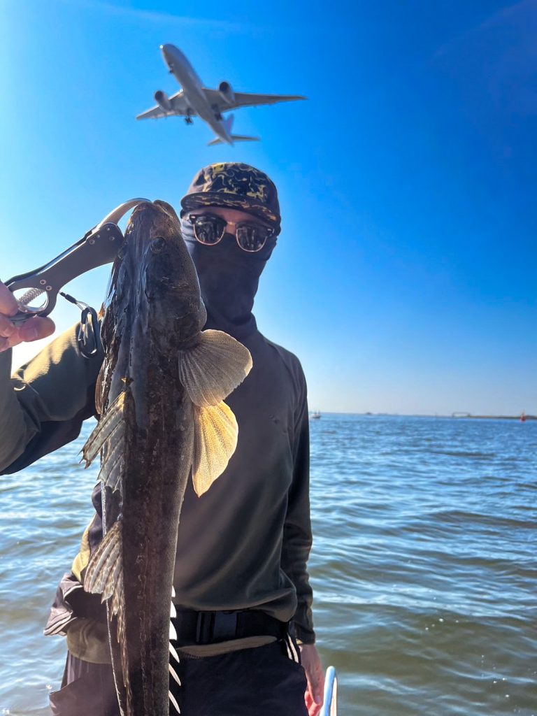 船の上で魚を釣り上げたHさんと映り込む飛行機。