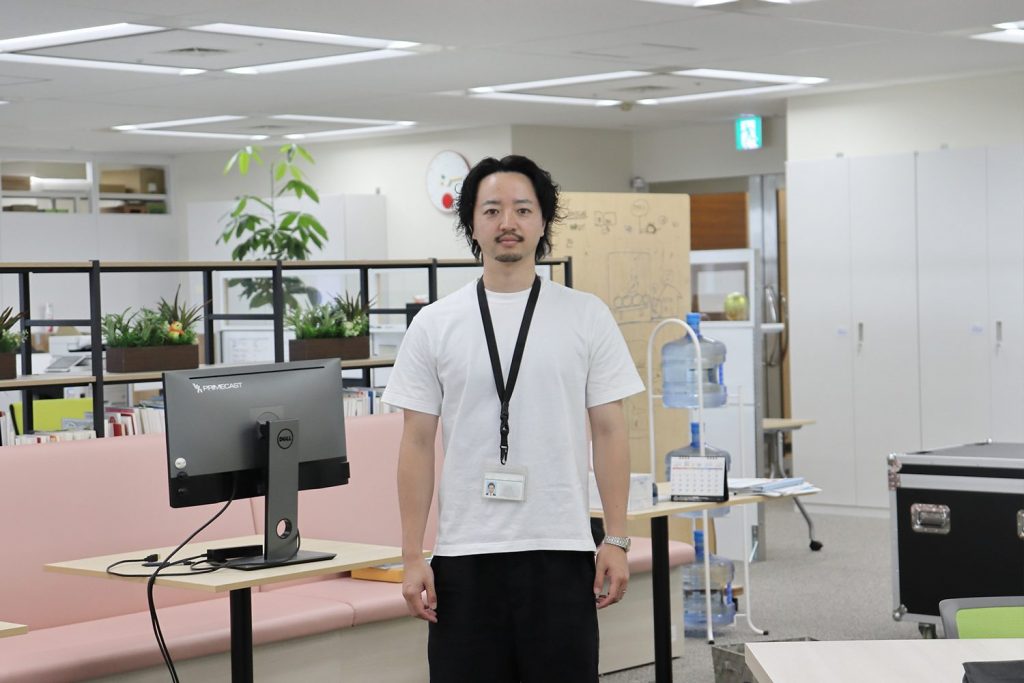 オフィスを背景にしたHさんの様子。