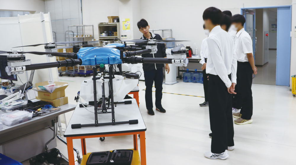 開発室でドローンを前に説明を受ける雄城台高校の生徒たち