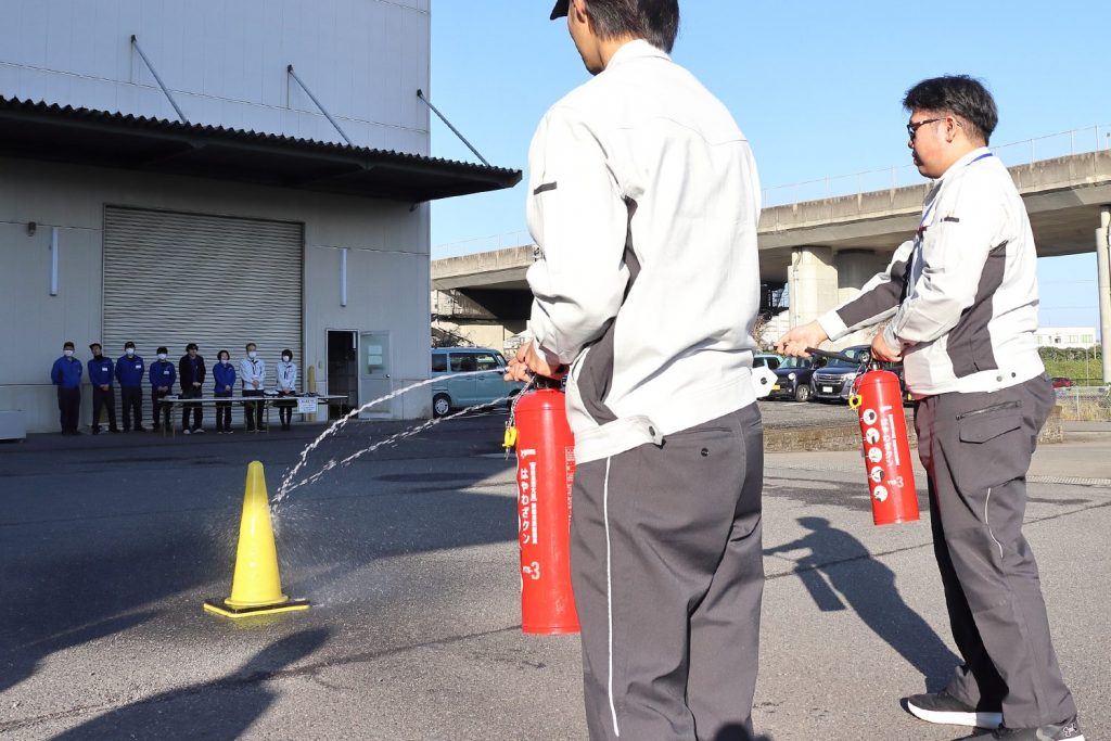 消火器で消火訓練をする曲工場の社員。