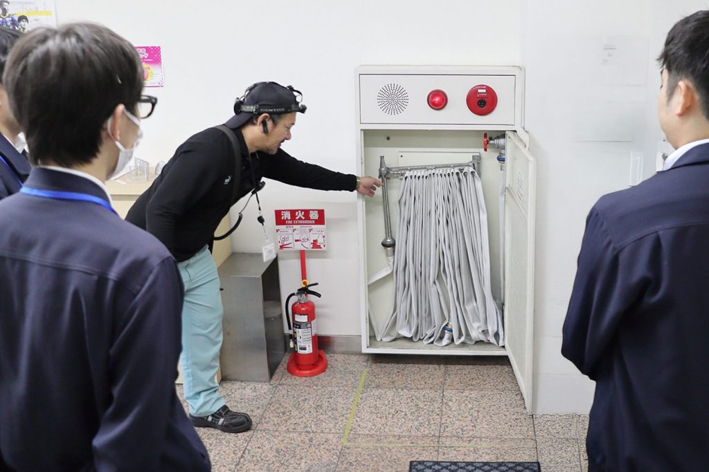 専門家から消火栓の扱い方を聞く社員。