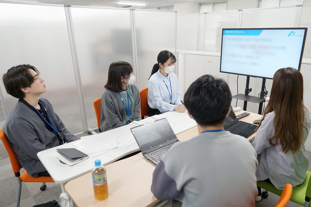 自社製品の活用現場を見学する新入社員。